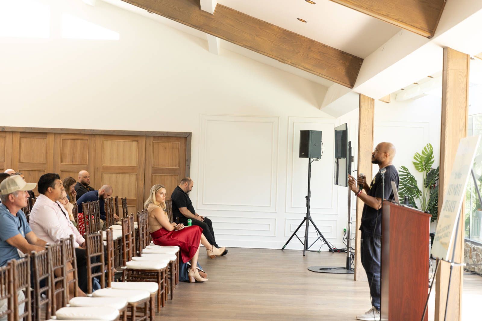 A man is standing at a podium giving a speech to a group of people sitting in chairs.