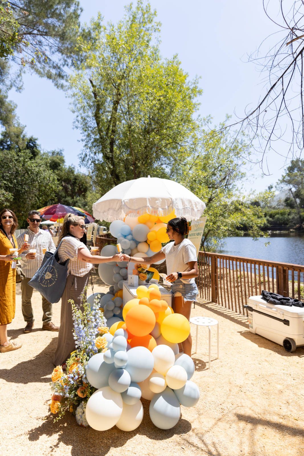 A woman is standing next to a cart filled with balloons.