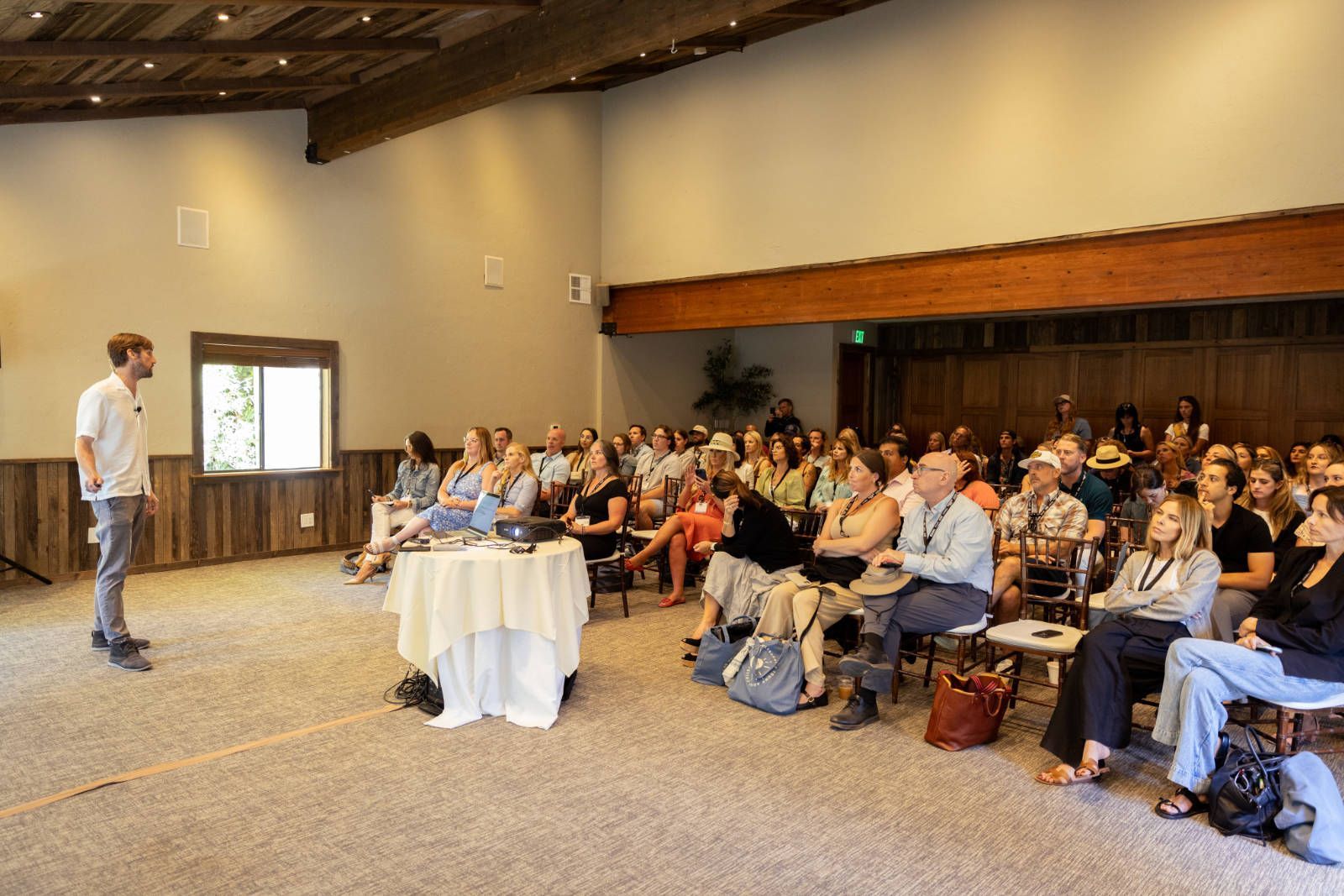 A man is giving a presentation to a large group of people sitting in a room.