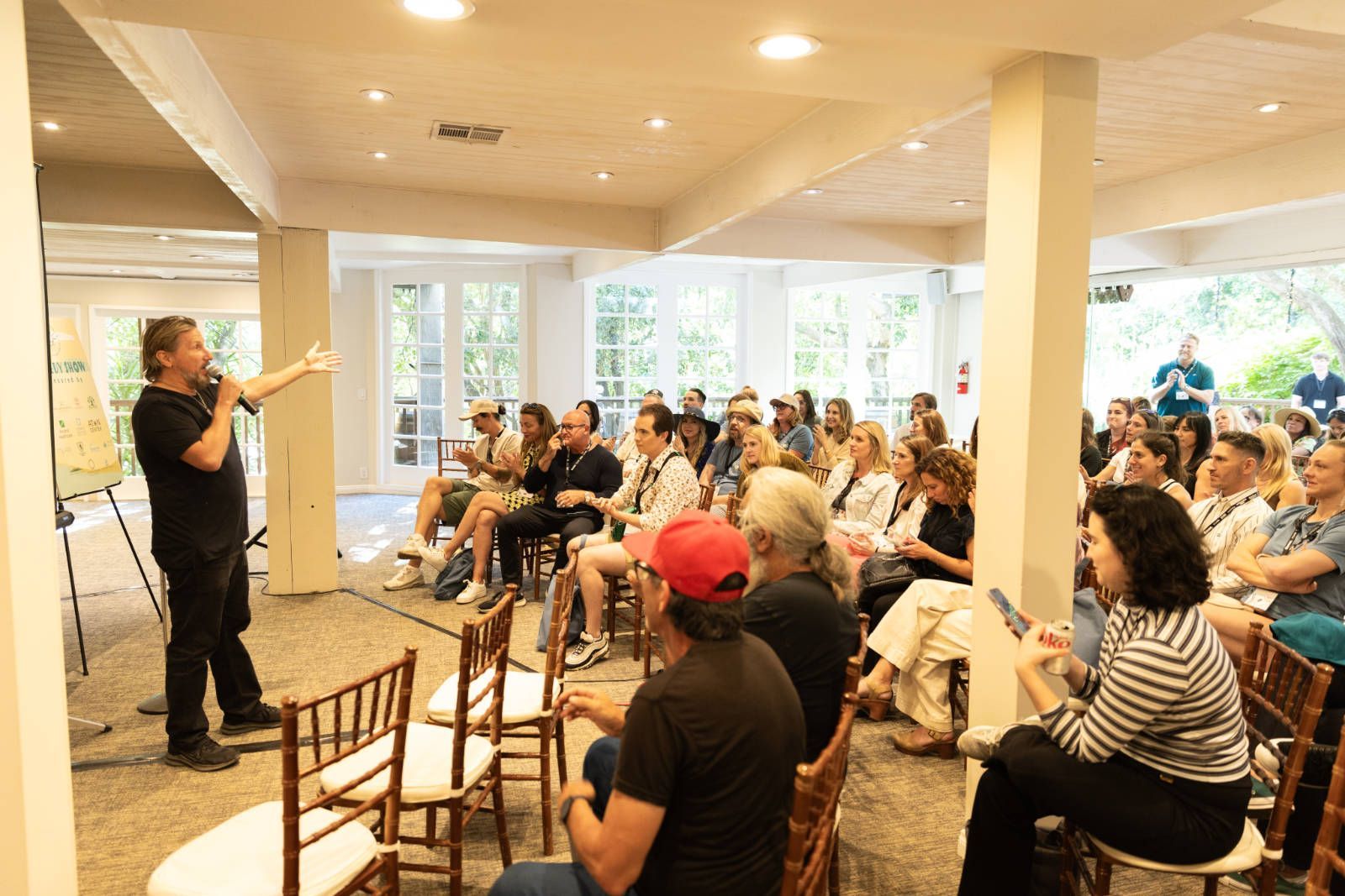 A man is giving a presentation to a large group of people sitting in chairs.