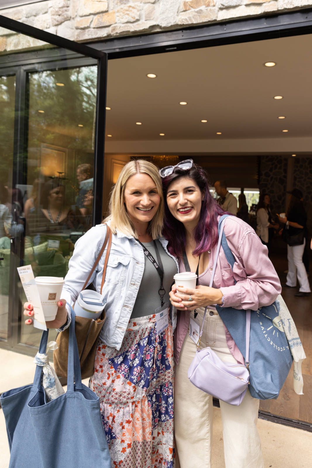 Two women are standing next to each other in front of a building.