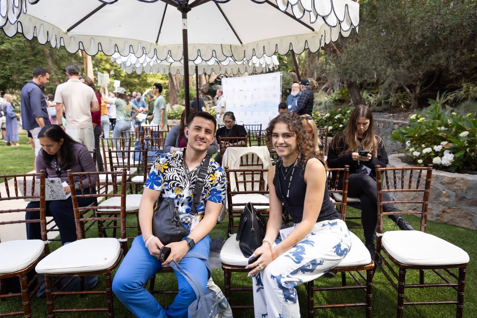 A man and a woman are sitting in chairs under an umbrella.