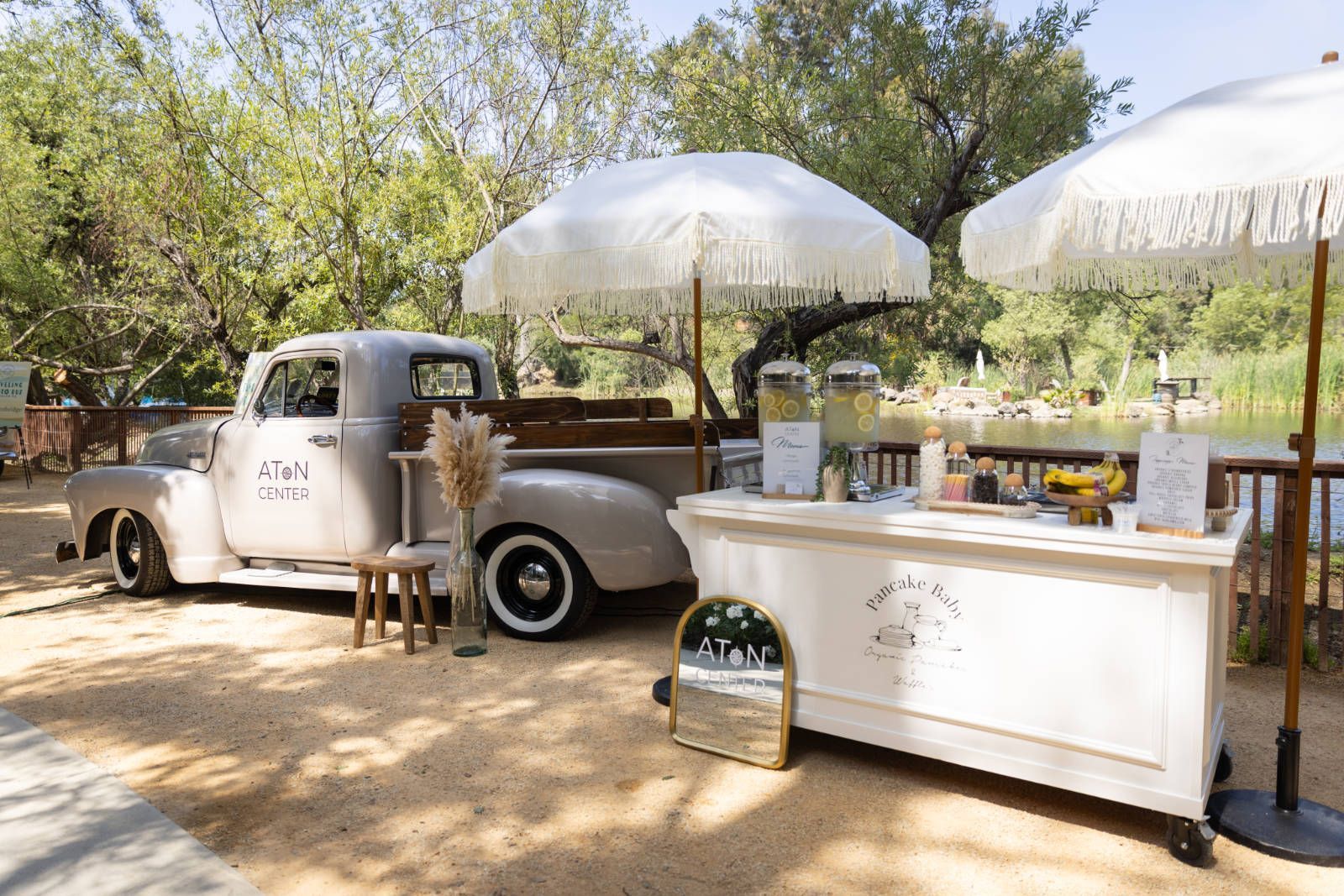 A white truck is parked next to a white cart with umbrellas.