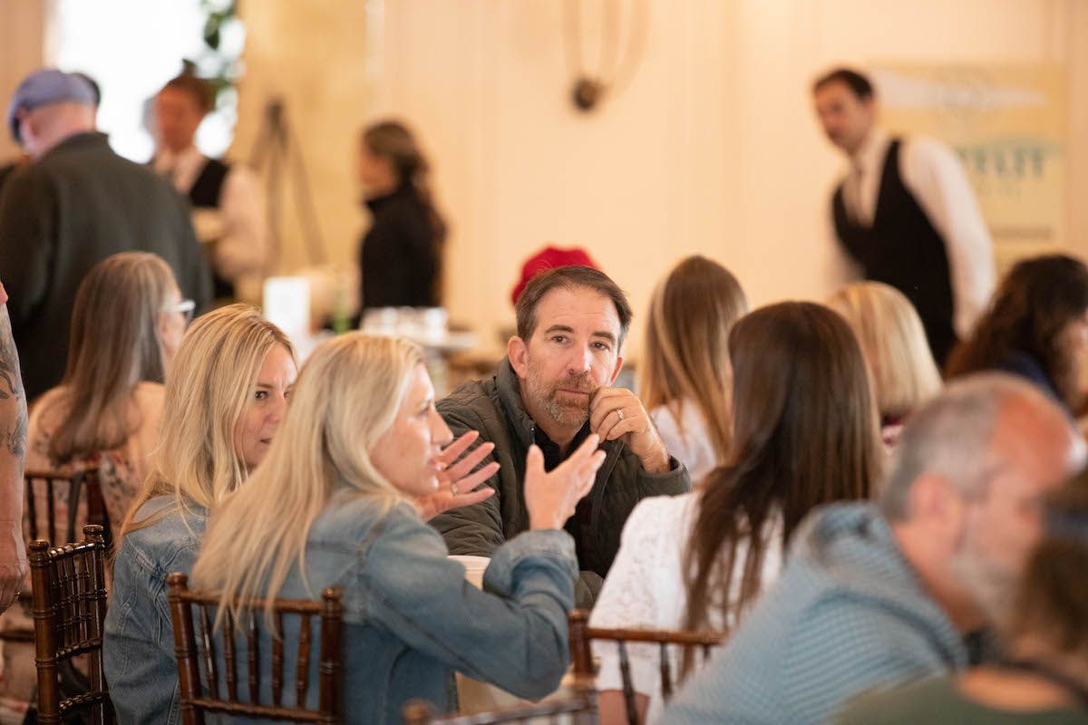 A group of people are sitting at a table talking to each other.