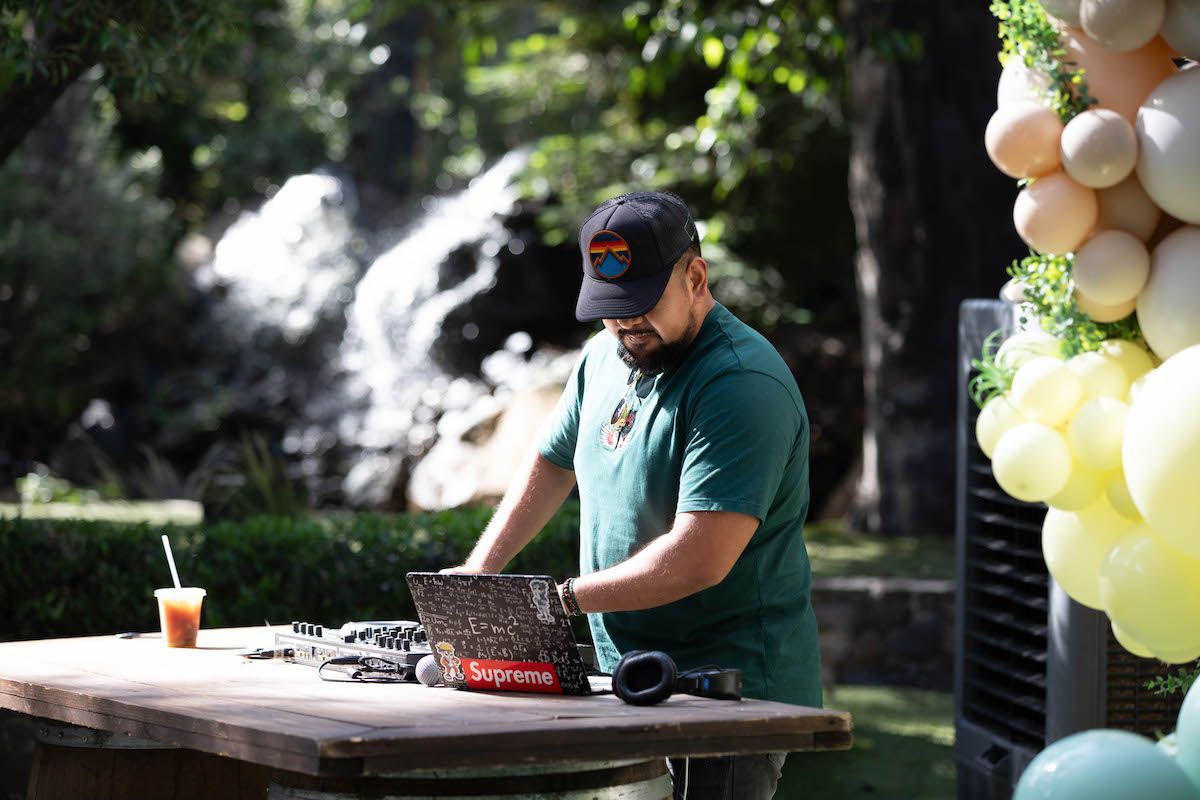 A man is standing at a table using a laptop computer.