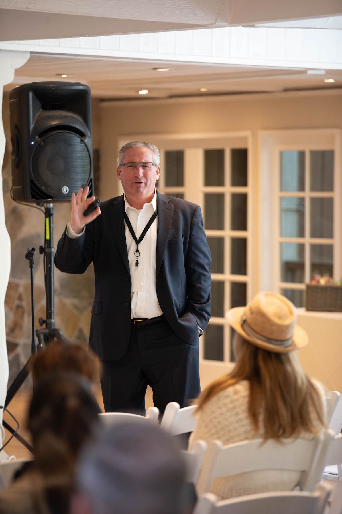 A man in a suit is giving a presentation to a group of people sitting in chairs.