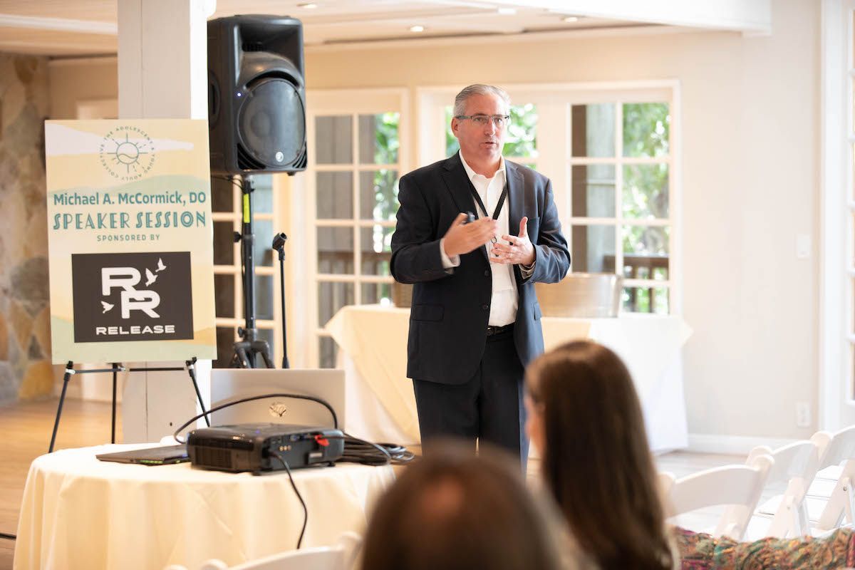 A man in a suit is giving a presentation to a group of people.