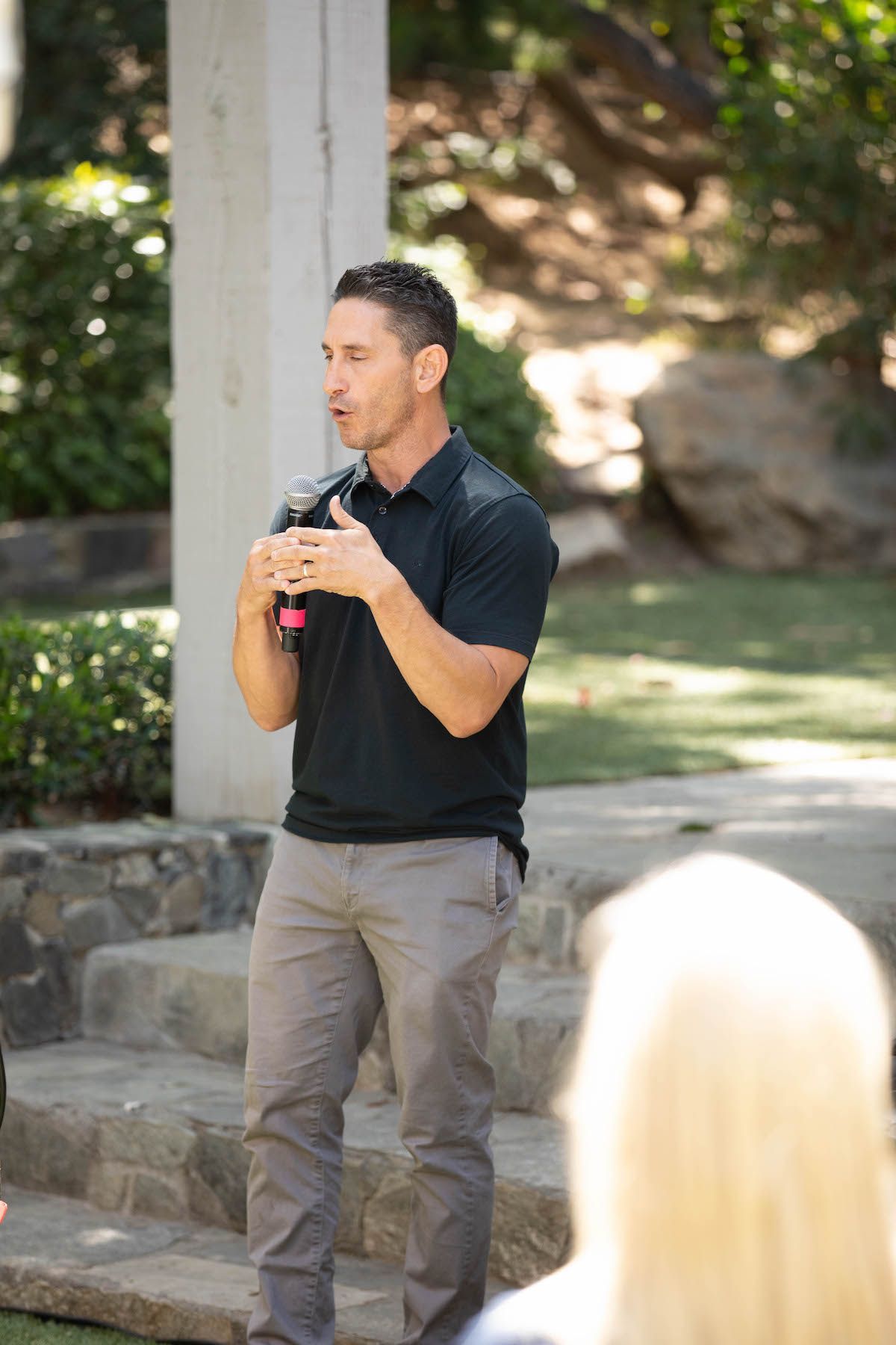 A man in a black shirt is standing in front of a microphone.