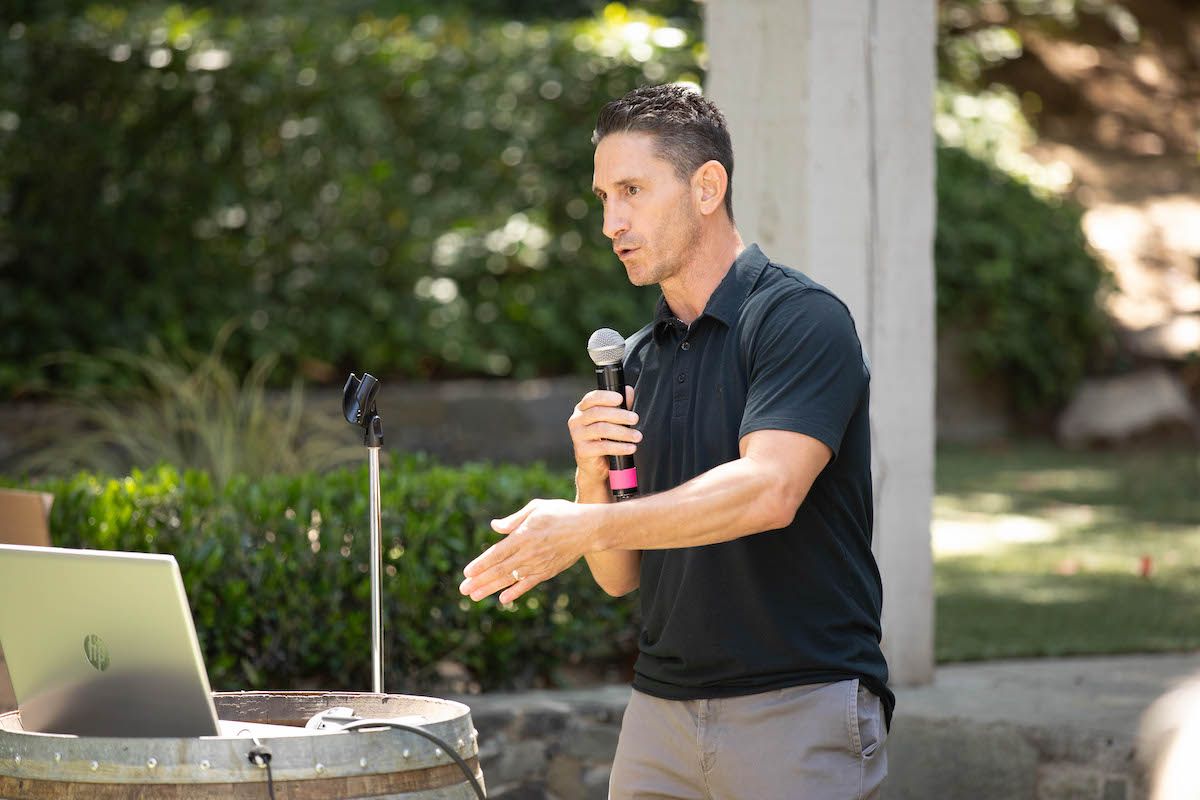 A man is standing in front of a microphone and a laptop.
