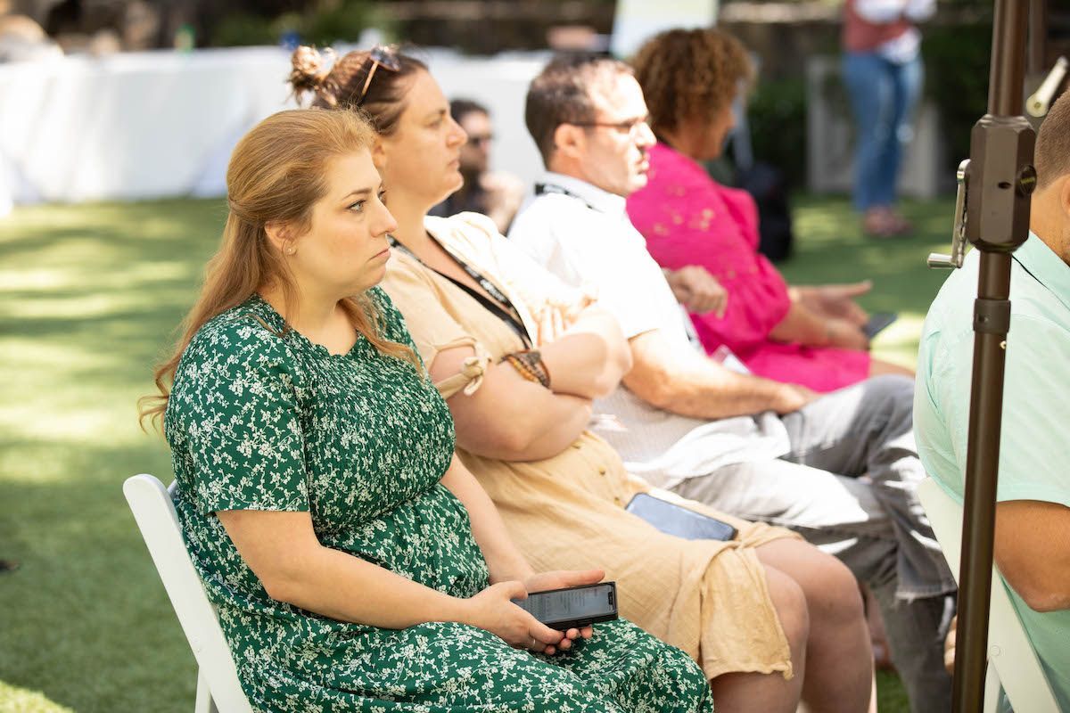 A group of people are sitting in chairs outside.