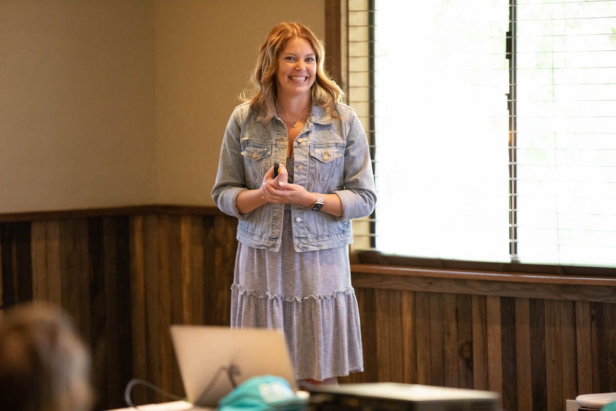 A woman is standing in front of a projector screen in a room.