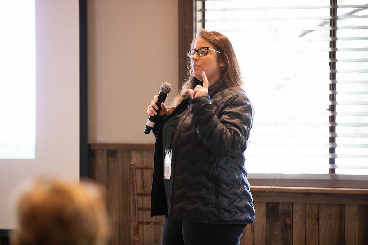 A woman is standing in front of a microphone and giving a presentation.