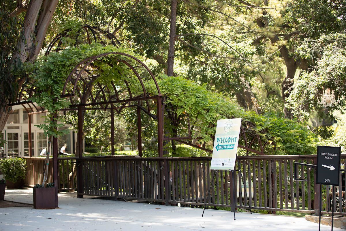 A wooden fence with a sign on it in a park surrounded by trees.