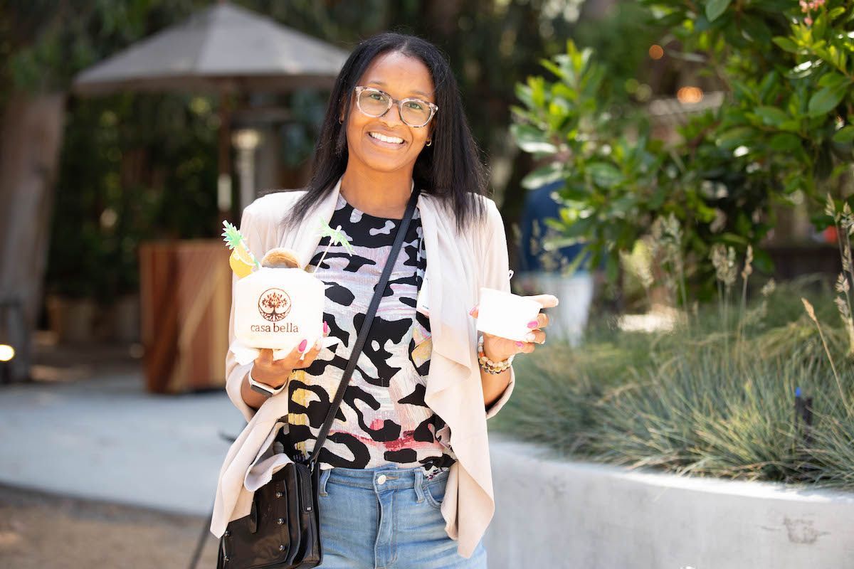 A woman is holding a cup of ice cream and smiling.