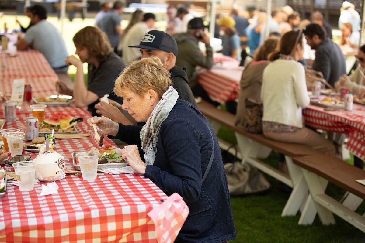 A woman is sitting at a picnic table looking at her phone.