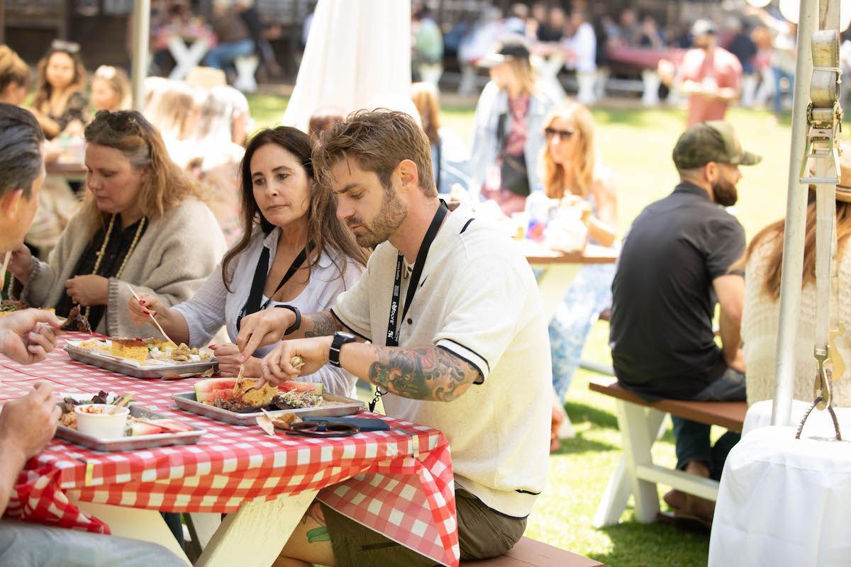 A group of people are sitting at a picnic table eating food.