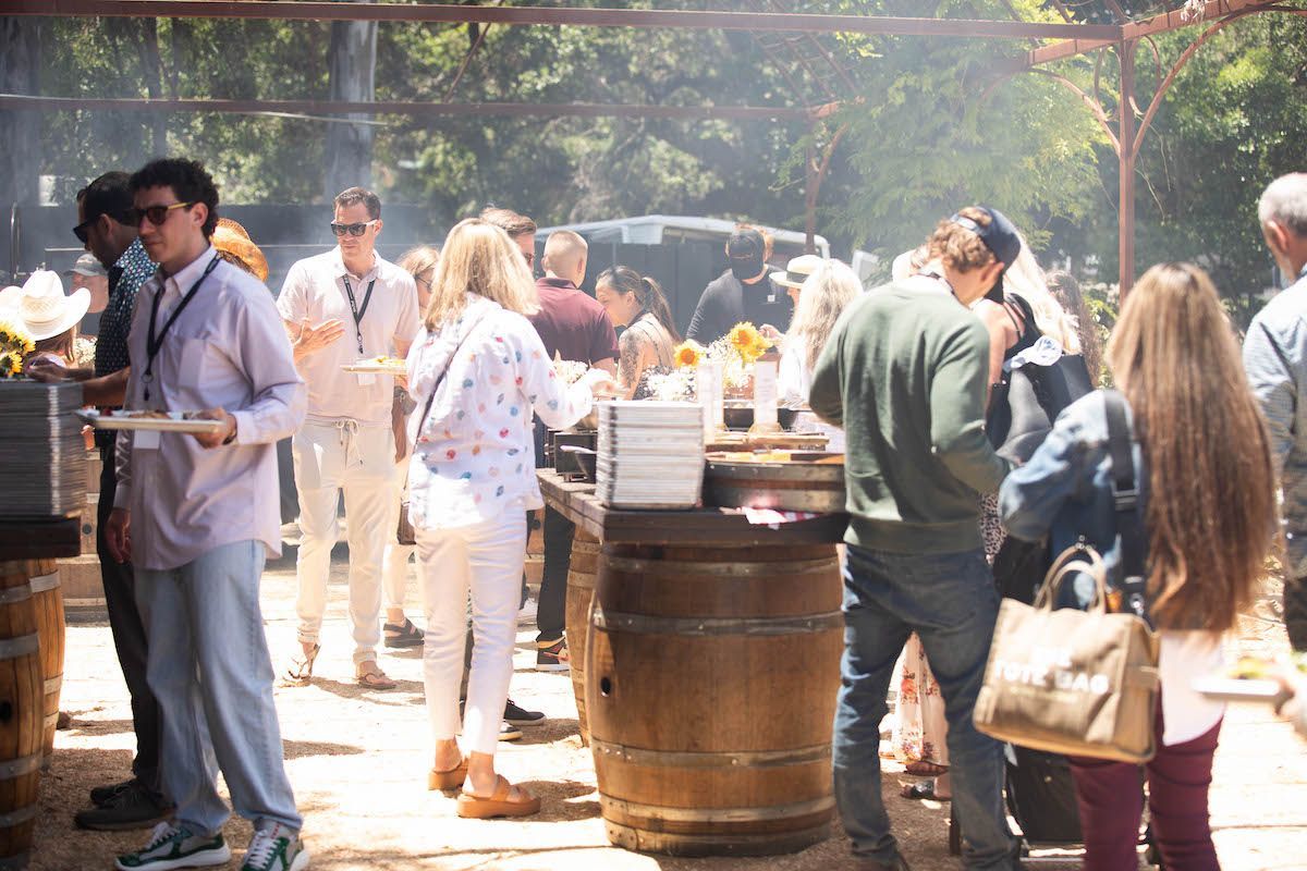 A group of people are standing around a wooden barrel.