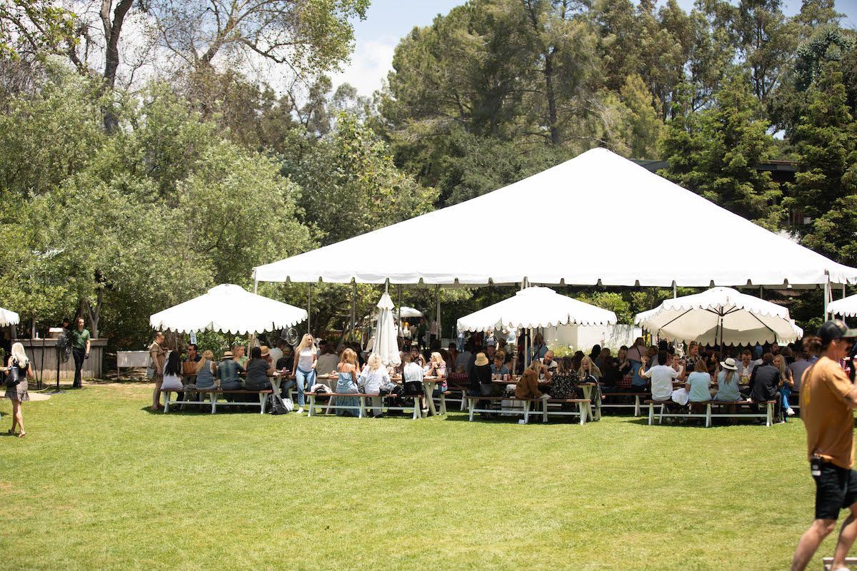 A group of people are sitting under a tent in a park