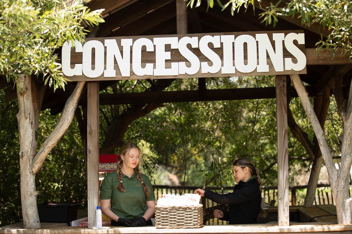 Two women standing under a sign that says concessions