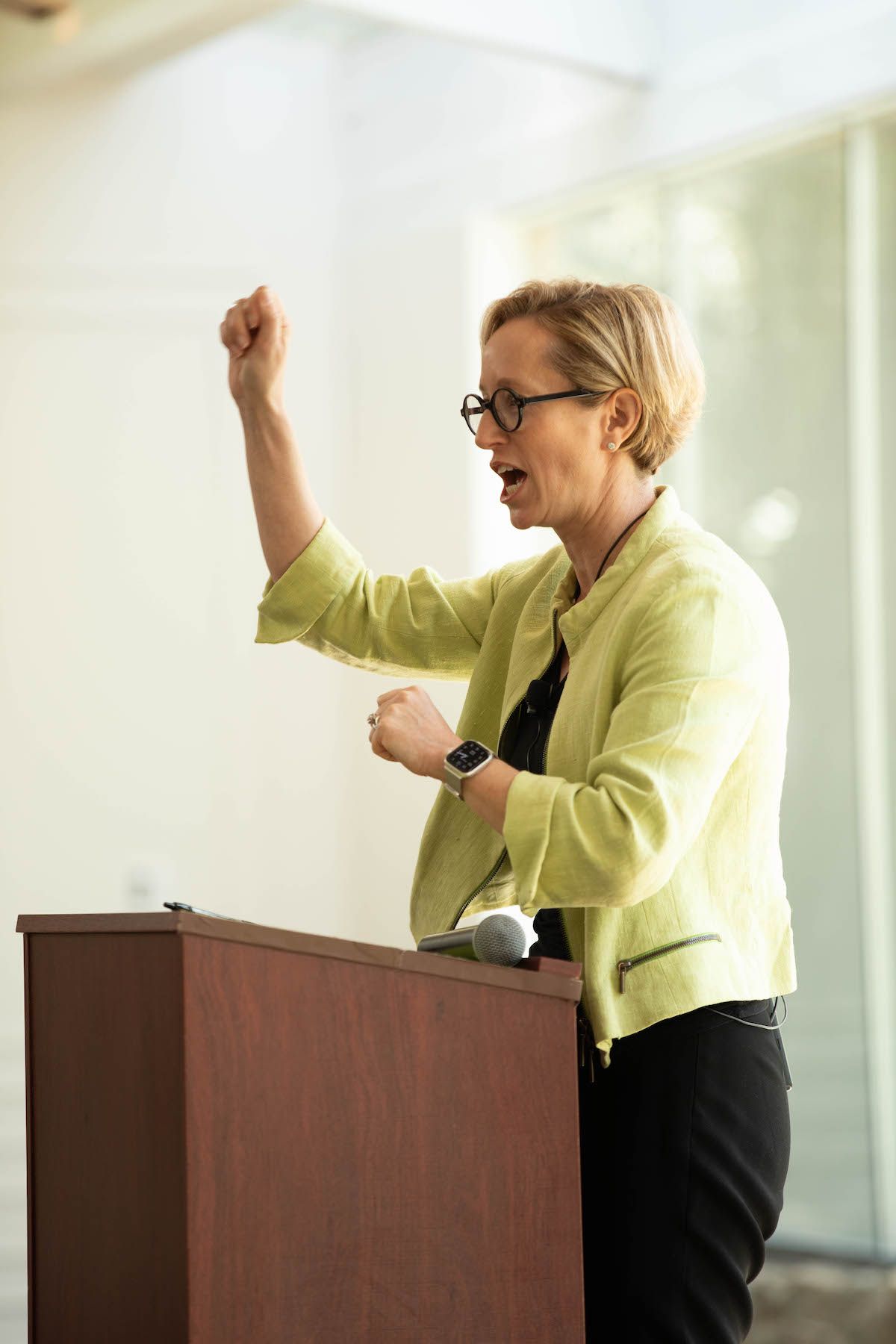 A woman is standing at a podium giving a speech with her fist in the air.