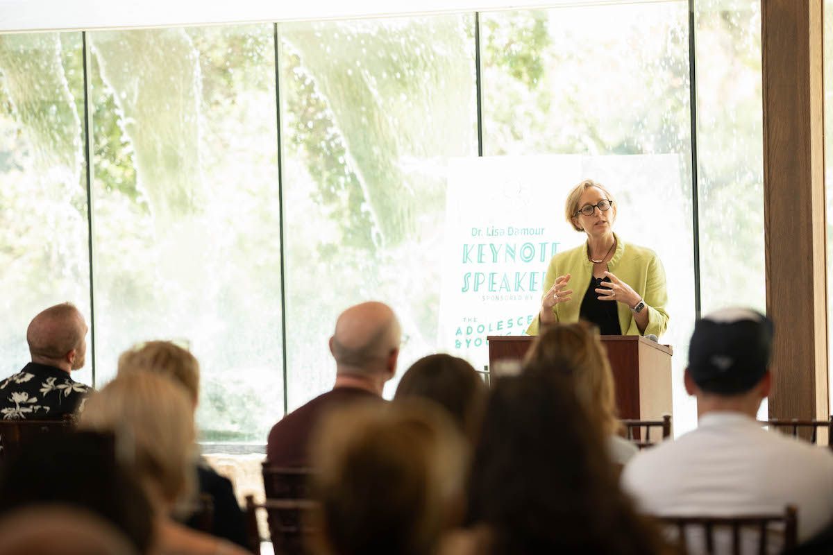 A woman is standing at a podium giving a presentation to a group of people.