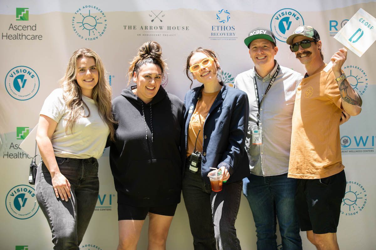 A group of people are posing for a picture in front of a wall.