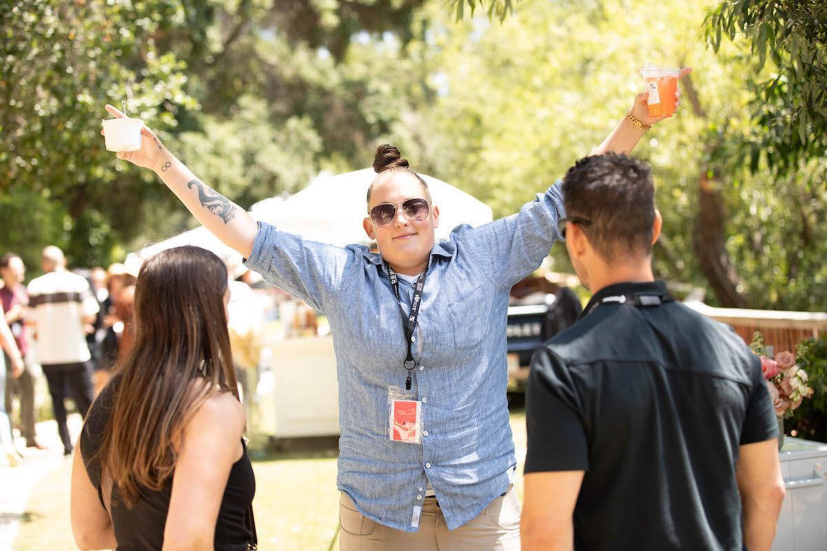 A woman is standing in front of a group of people with her arms in the air.