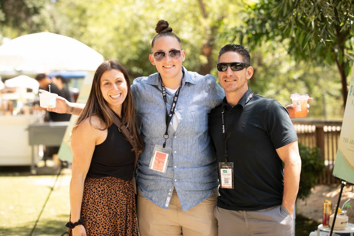 Three people are posing for a picture together in a park.