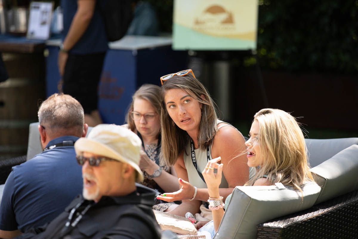 A group of people are sitting on a couch talking to each other.
