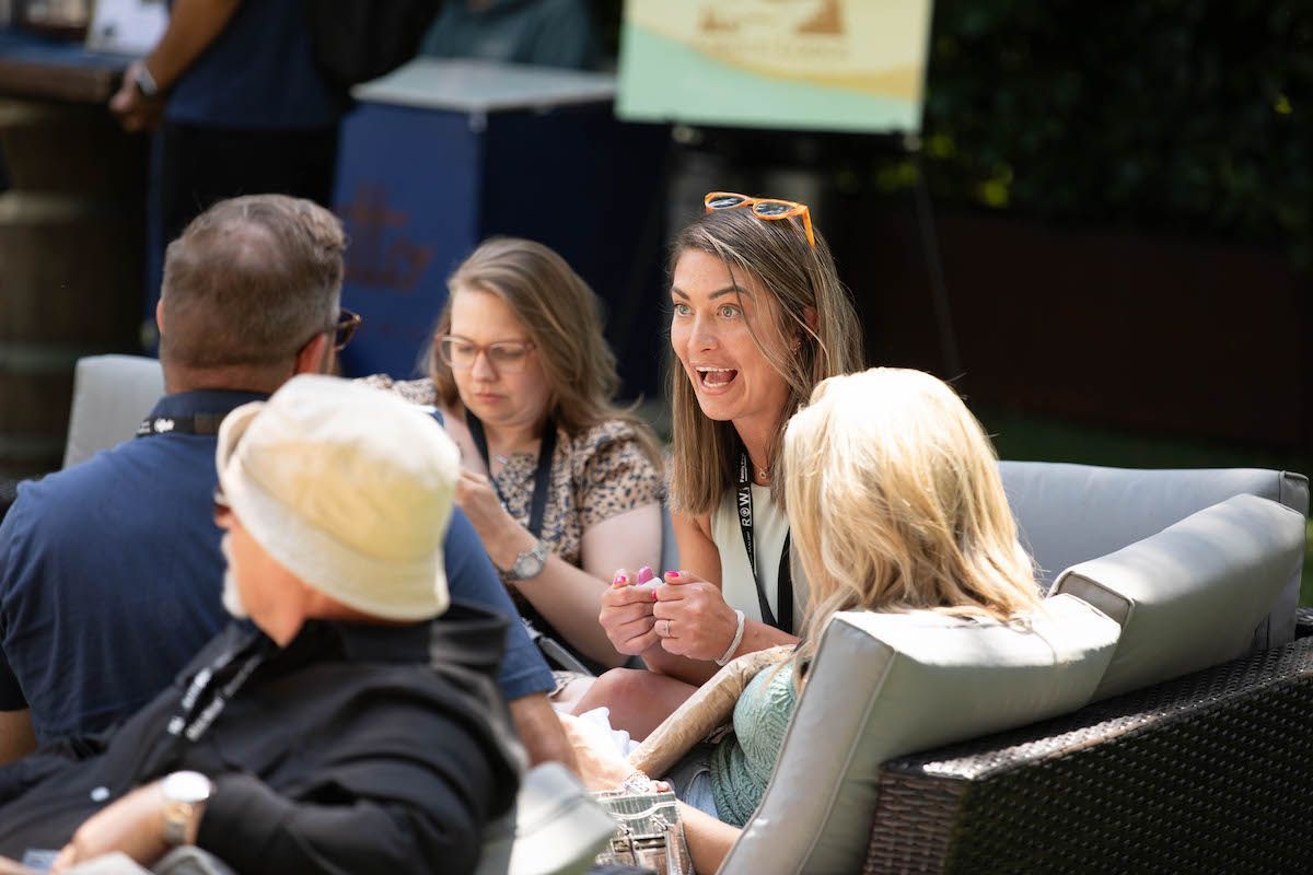 A group of people are sitting on a couch talking to each other.