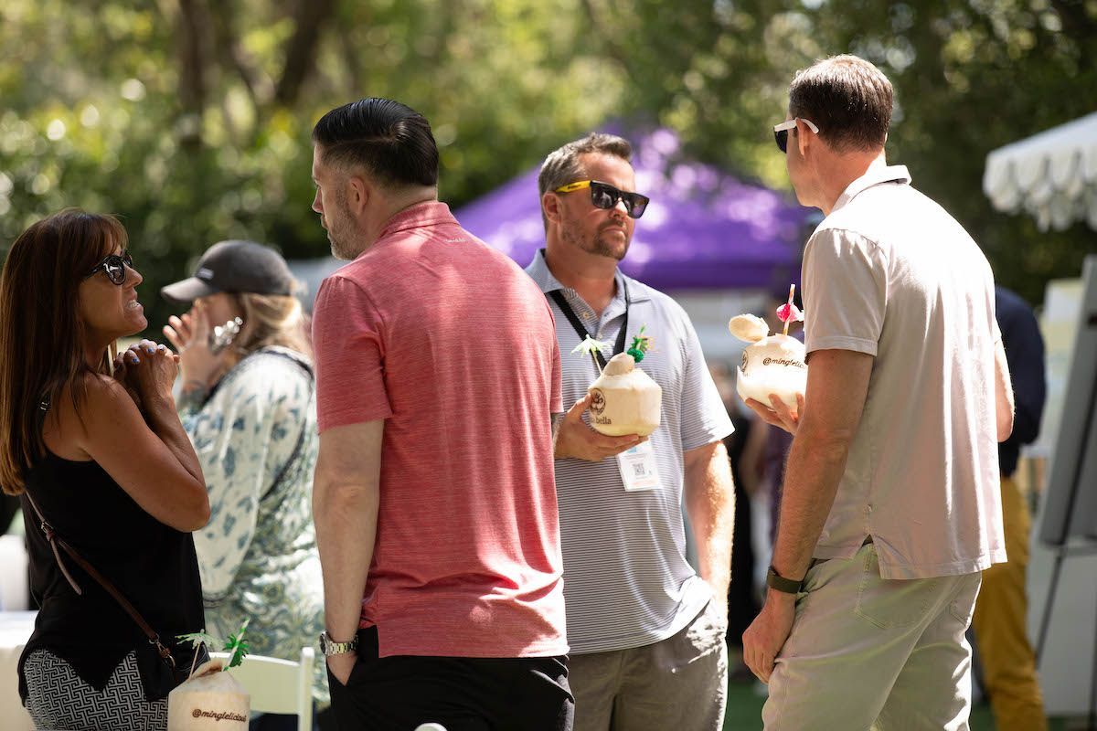 A group of people are standing around a table talking to each other.