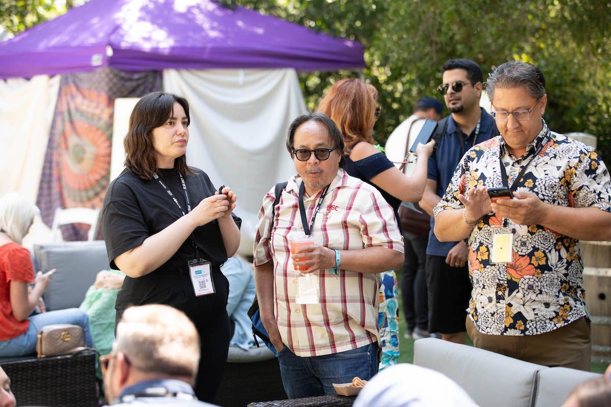 A group of people are standing in front of a purple tent.