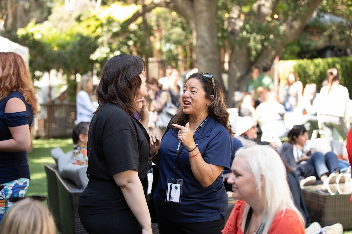 A group of women are standing in a park talking to each other.