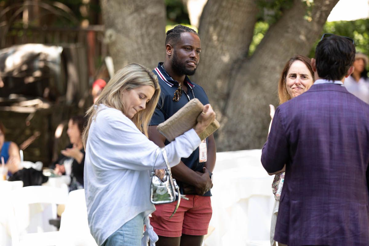 A group of people are standing around a table talking to each other.