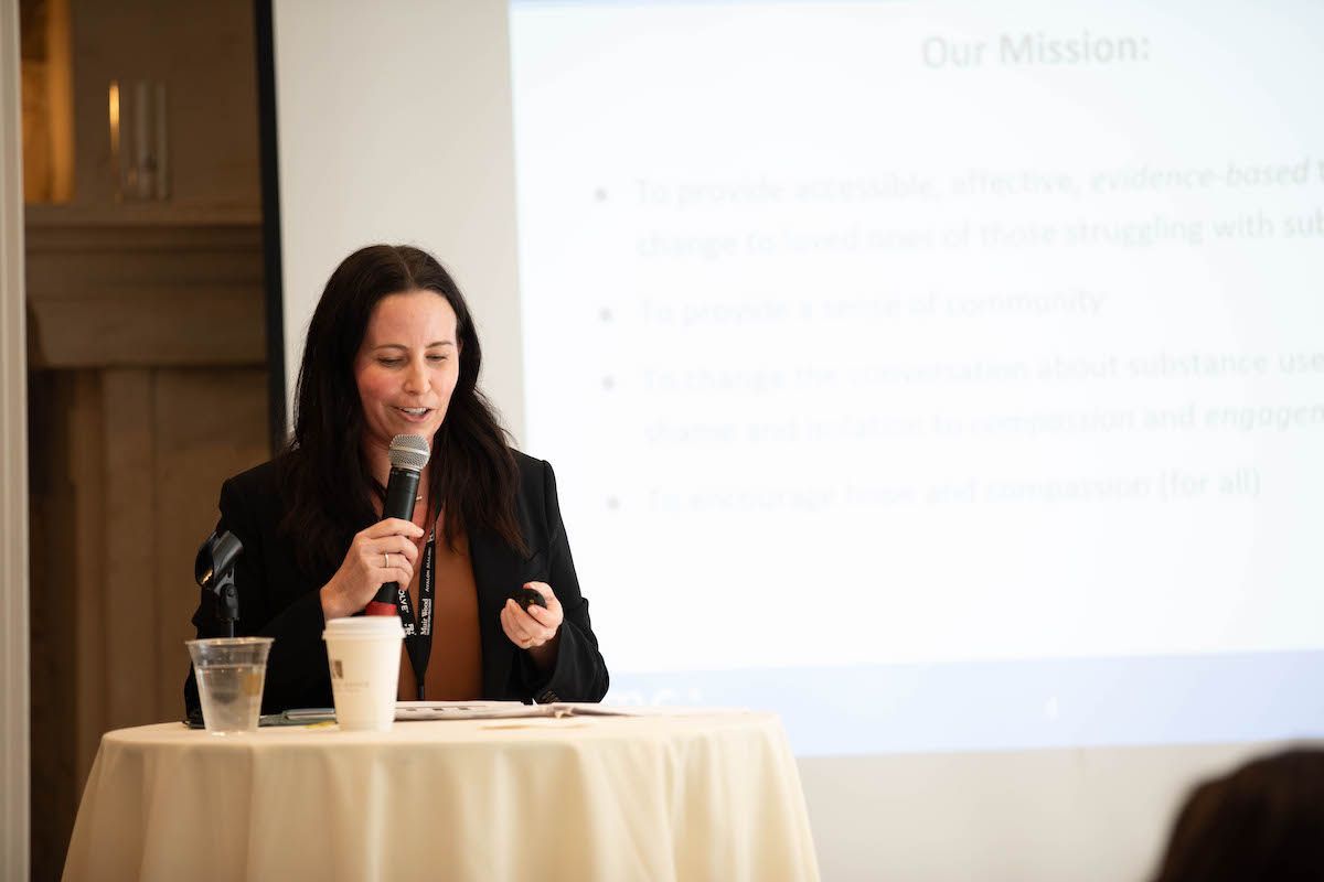 A woman is sitting at a table holding a microphone.