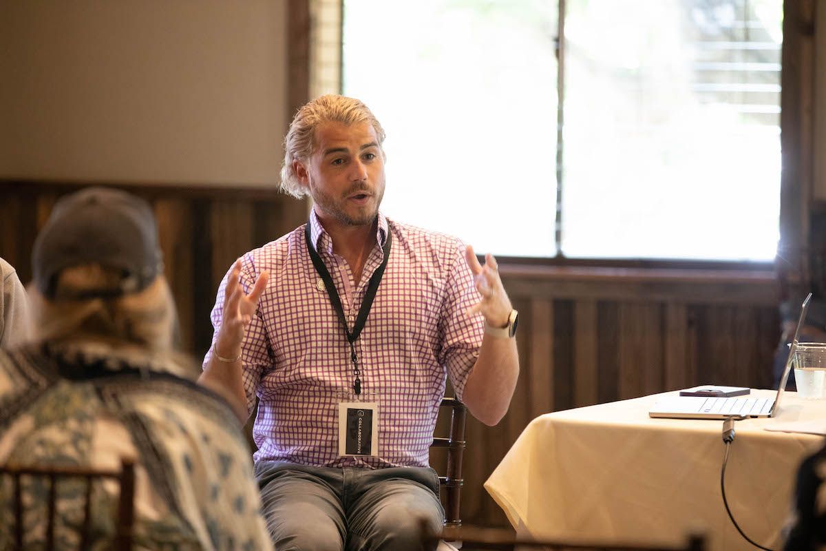 A man is sitting at a table talking to a group of people.