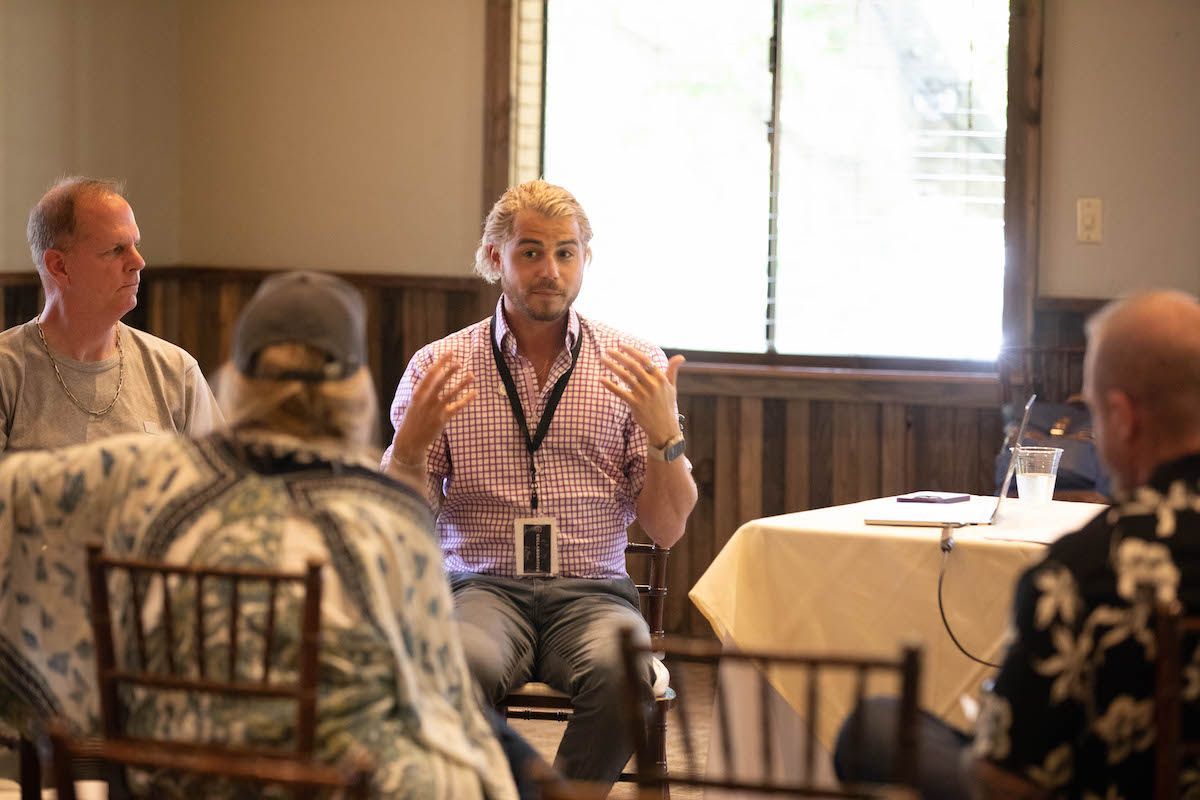 A group of people are sitting around a table talking to each other.