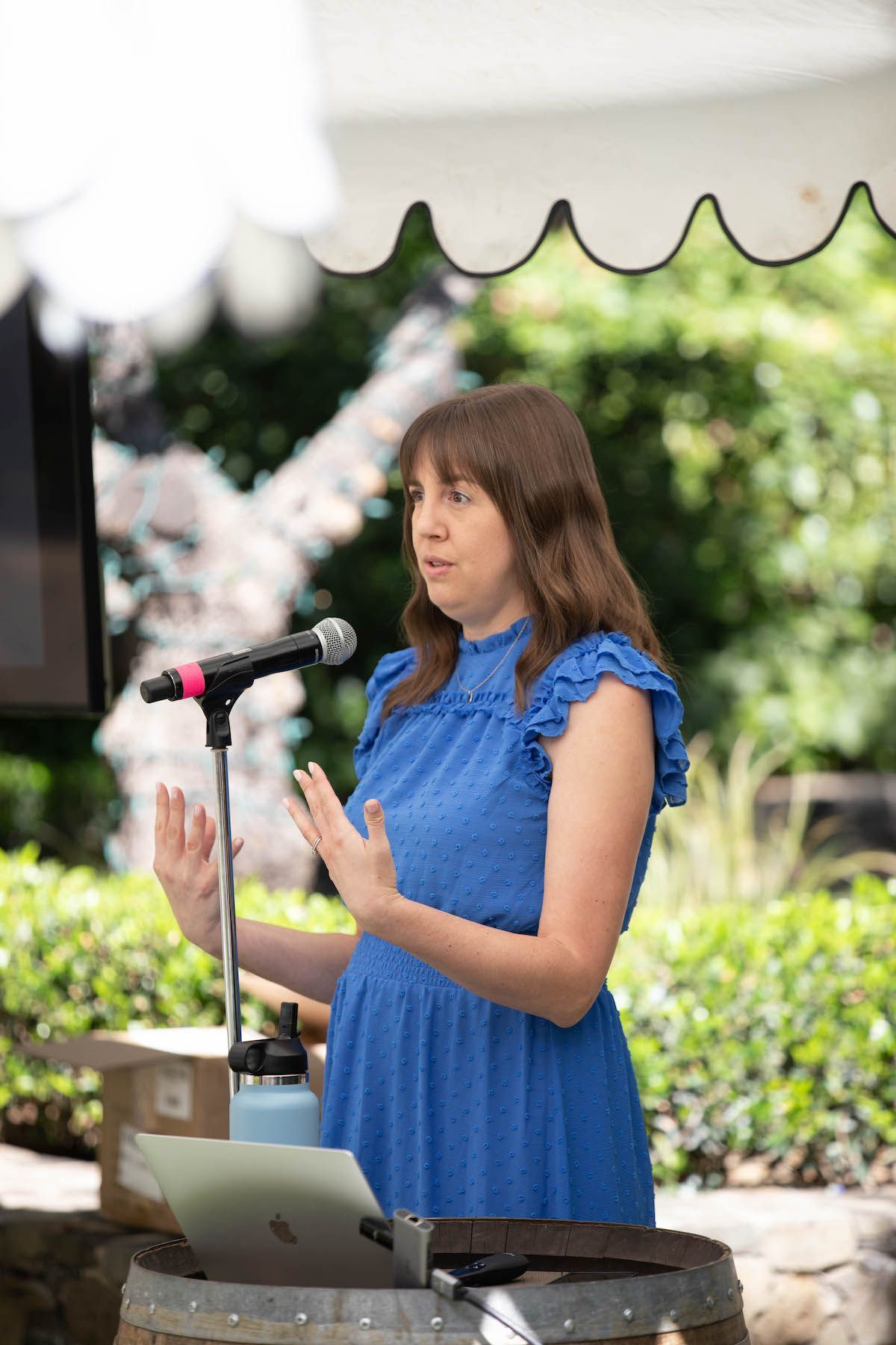 A woman in a blue dress is standing in front of a microphone.