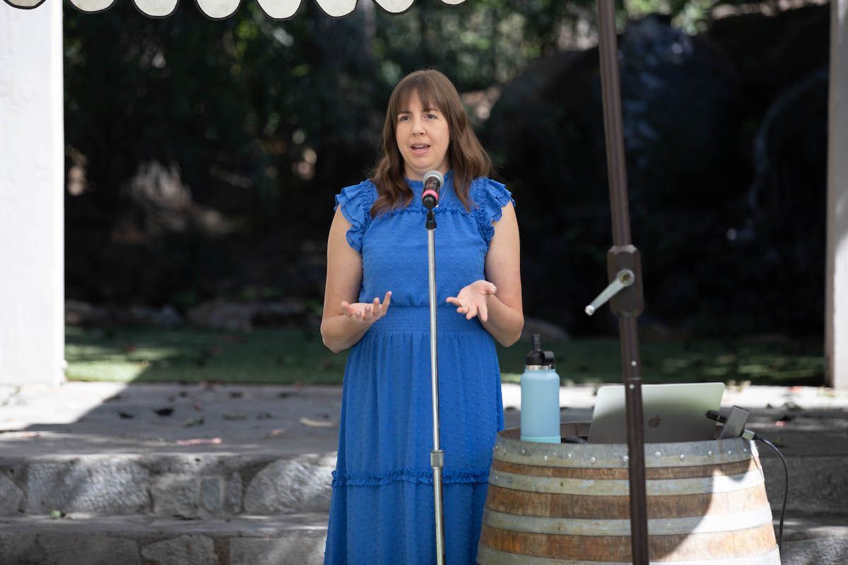 A woman in a blue dress is standing in front of a microphone.