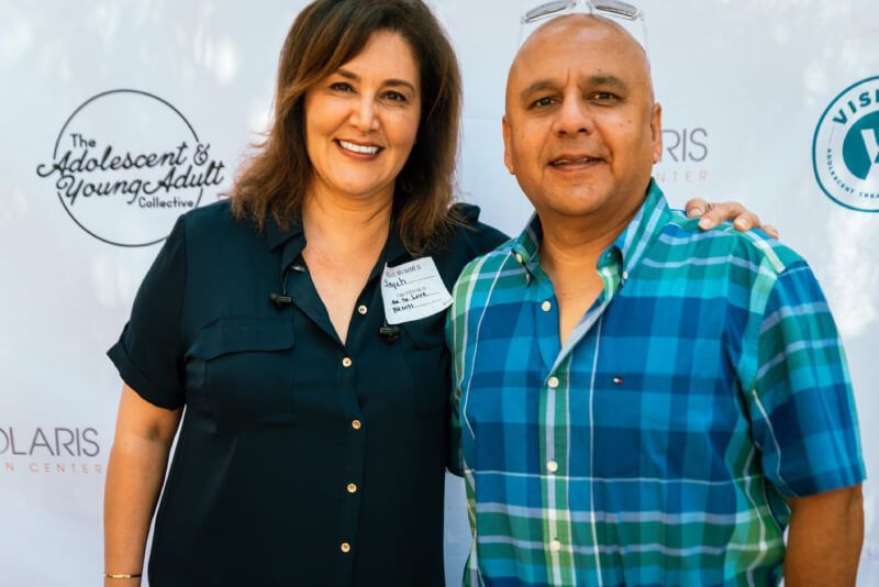 A man and a woman are posing for a picture . the man is wearing a plaid shirt.