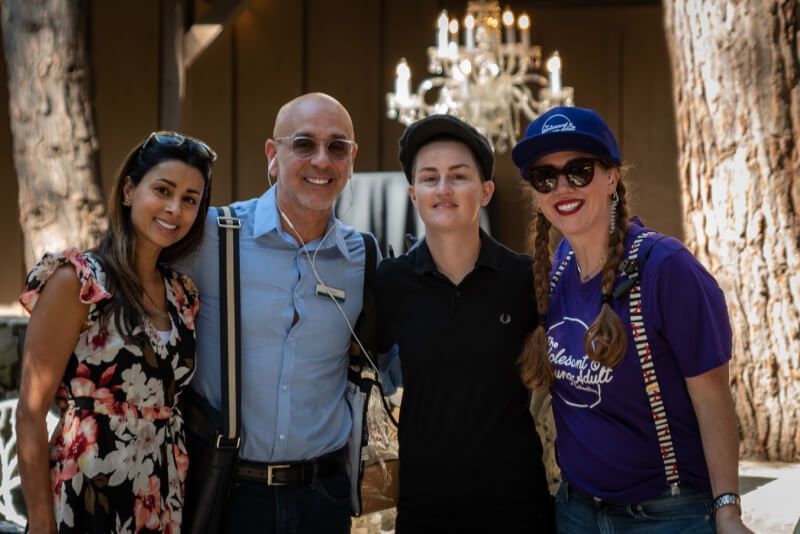 A group of people posing for a picture in front of a chandelier.