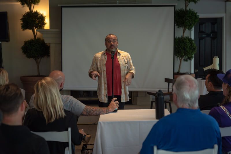 A man is giving a presentation to a group of people sitting at a table.