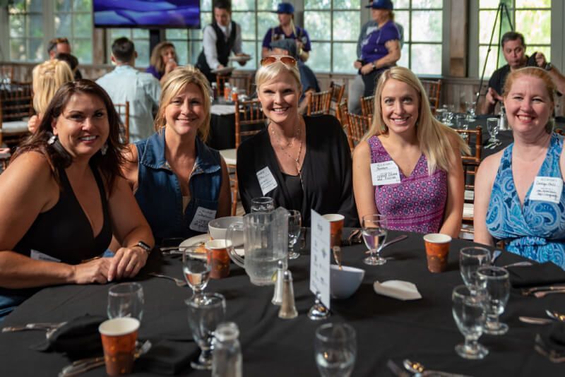 A group of women are sitting at a table with glasses of water.