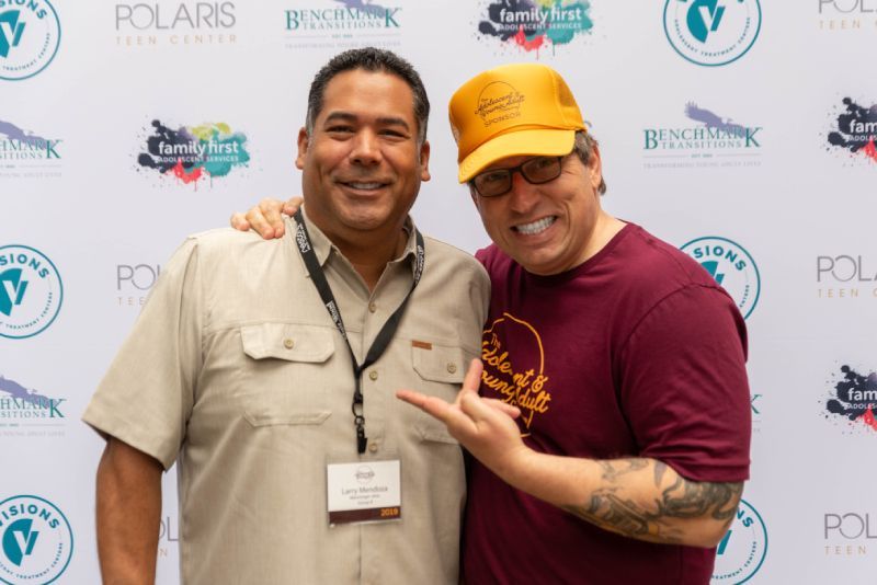 Two men are posing for a picture in front of a wall that says polaris.
