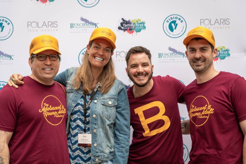 A group of people wearing maroon shirts and yellow hats are posing for a picture.