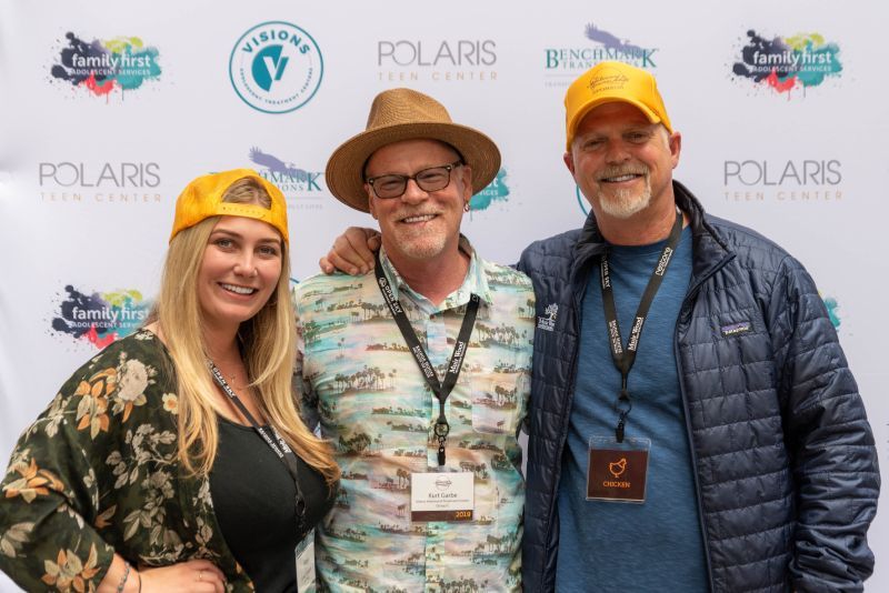 Three people are posing for a picture in front of a polaris banner.