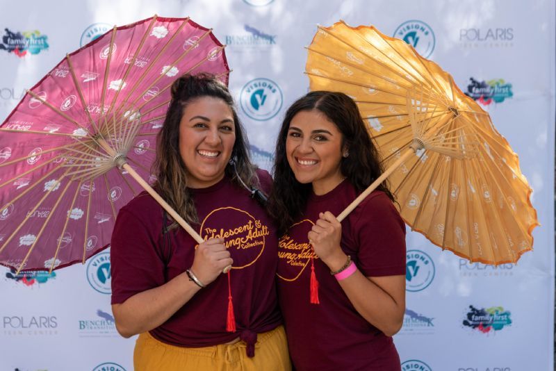 Two women are posing for a picture while holding umbrellas.