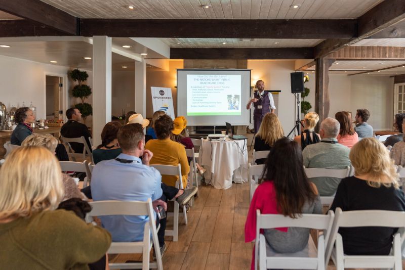 A group of people are sitting in chairs in front of a projector screen.