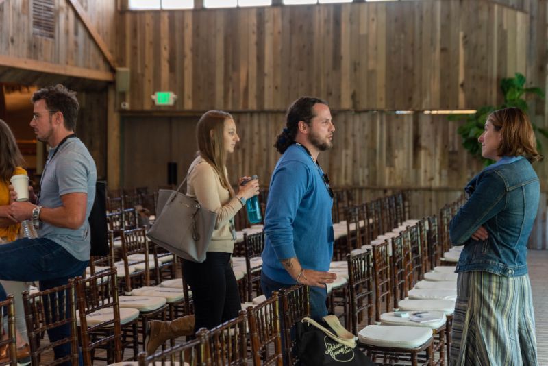 A group of people are standing in a room talking to each other.