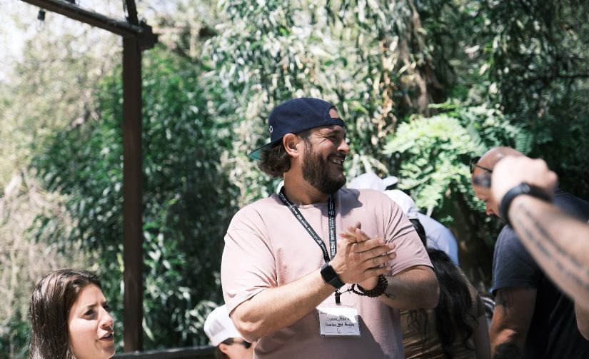 A man wearing a name tag is standing in a crowd of people.